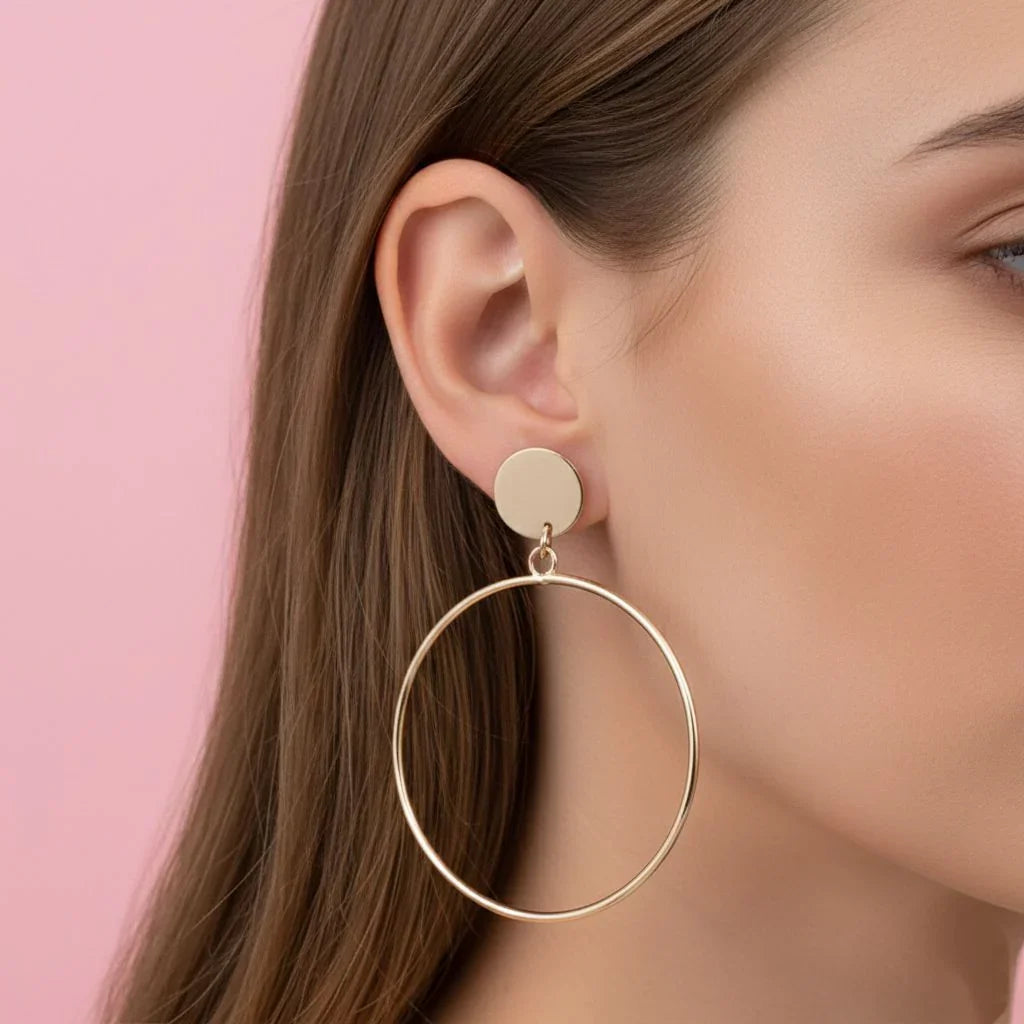 Gold hoop earring worn by a person with a pink background