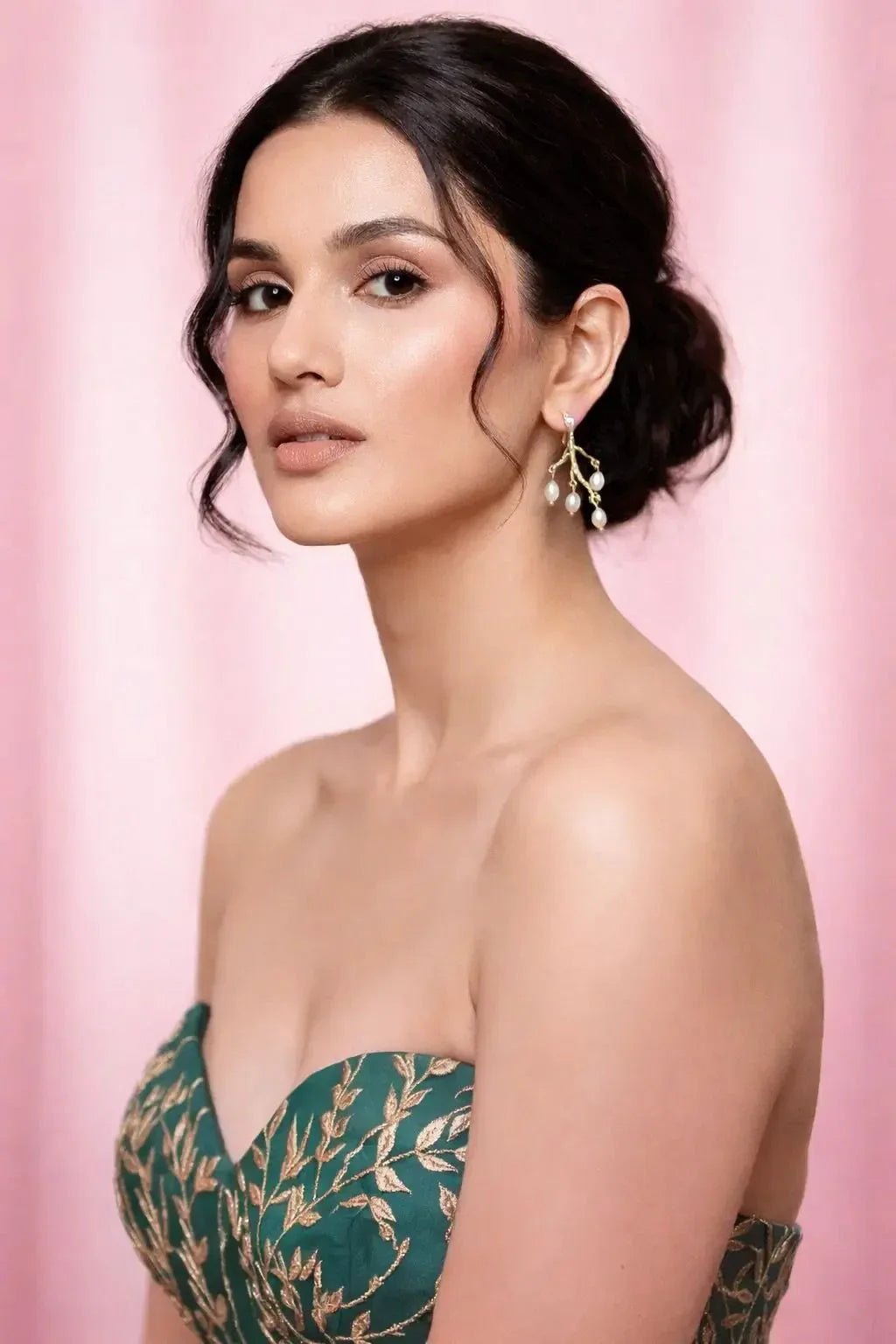Woman wearing a green strapless dress with floral patterns against a pink background