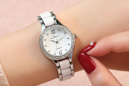 Silver wristwatch with diamond accents on a wrist with red nail polish.