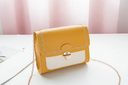 Yellow handbag with a gold chain on a white surface