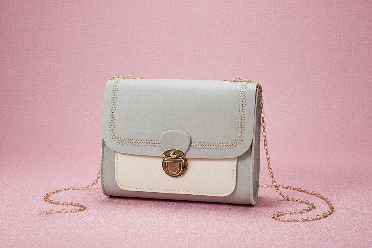 Gray and white handbag with gold chain on a light background