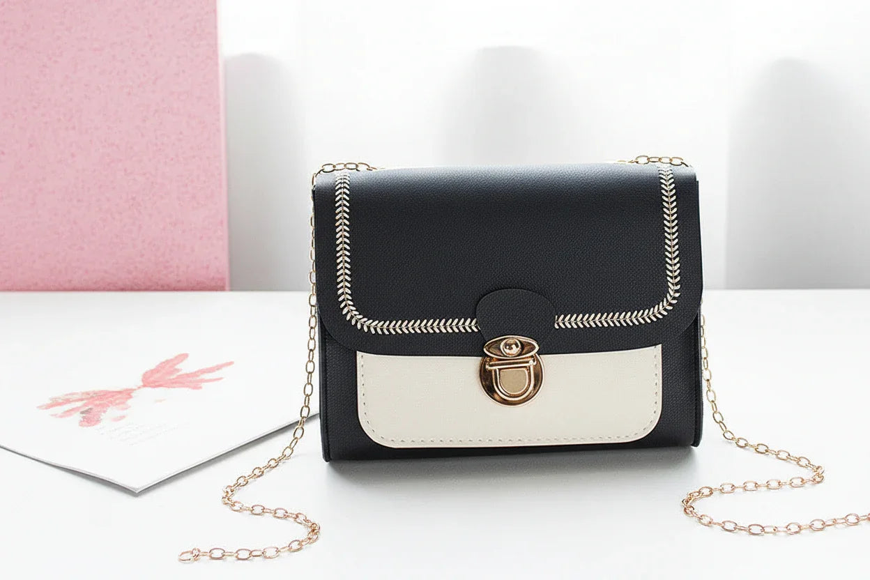 Black and white handbag with a gold chain on a light background