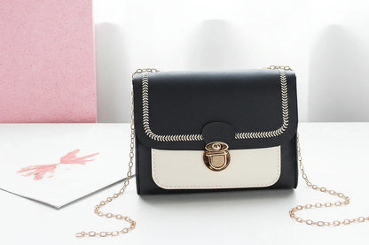 Black and white handbag with a gold chain on a light background