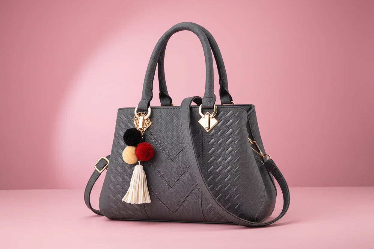Gray handbag with decorative tassels on a white background
