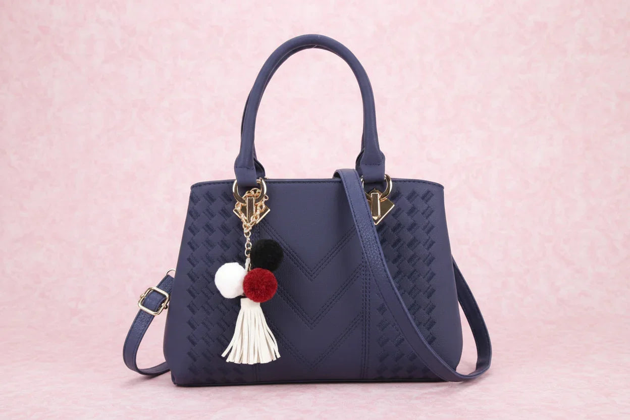 Navy blue handbag with decorative tassel on a white background