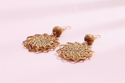 Pair of woven earrings with wooden beads on a light background