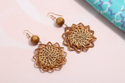 Pair of woven earrings on a textured fabric background