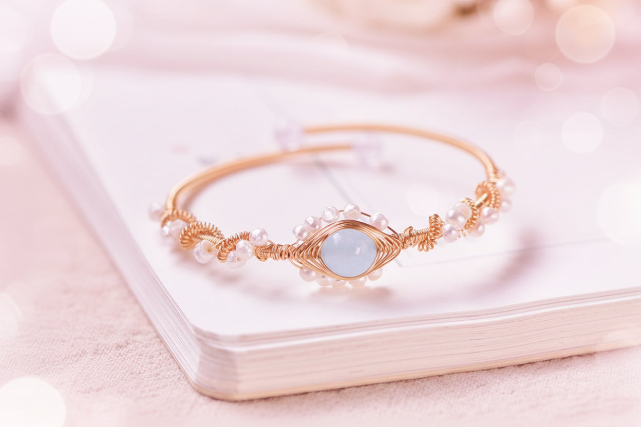 Gold bracelet with a blue gemstone on a white surface