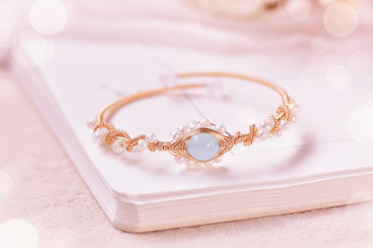 Gold bracelet with a blue gemstone on a white surface