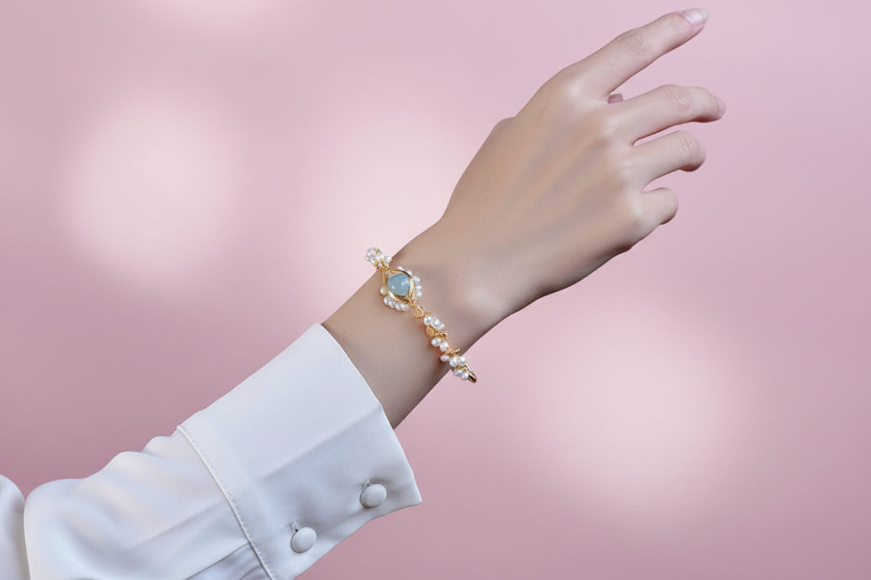 Hand wearing a gold bracelet with a blue gemstone against a dark background