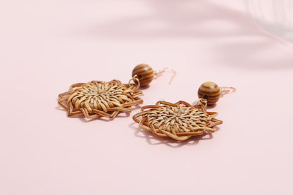 Pair of woven earrings with wooden beads on a light background