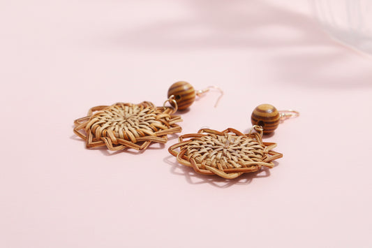 Pair of woven earrings with wooden beads on a light background