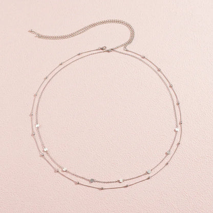 Layered gold necklace on a beige background