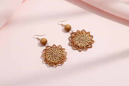 Pair of woven earrings on a textured fabric background