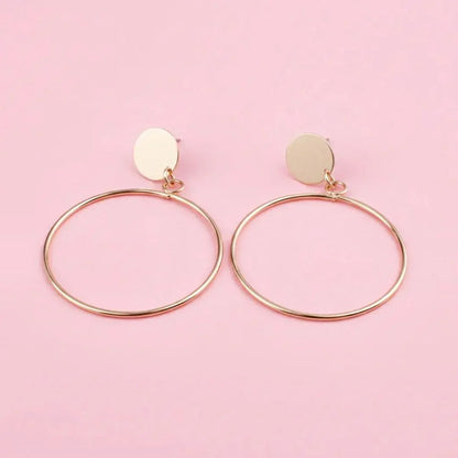 Gold hoop earrings on a pink background