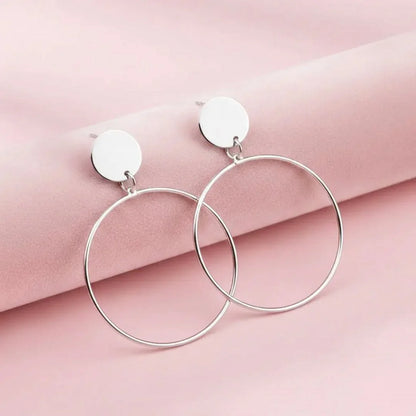 Silver hoop earrings on a pink fabric background