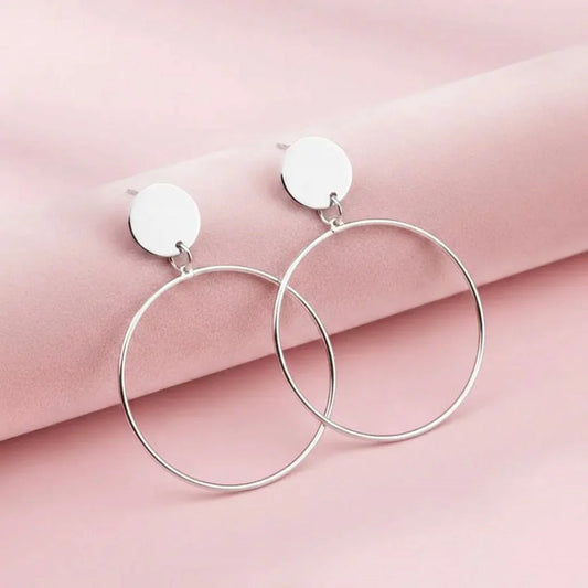 Silver hoop earrings on a pink fabric background