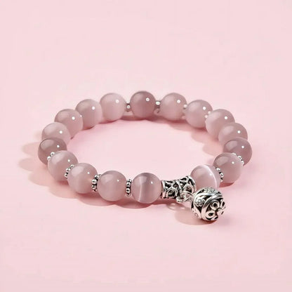 Pink beaded bracelet with a silver charm on a pink background