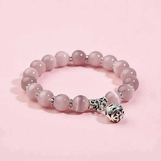 Pink beaded bracelet with a silver charm on a pink background