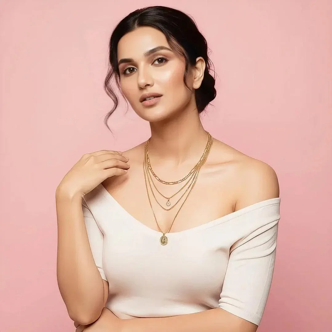 Woman wearing a white off-shoulder top and gold necklaces on a pink background