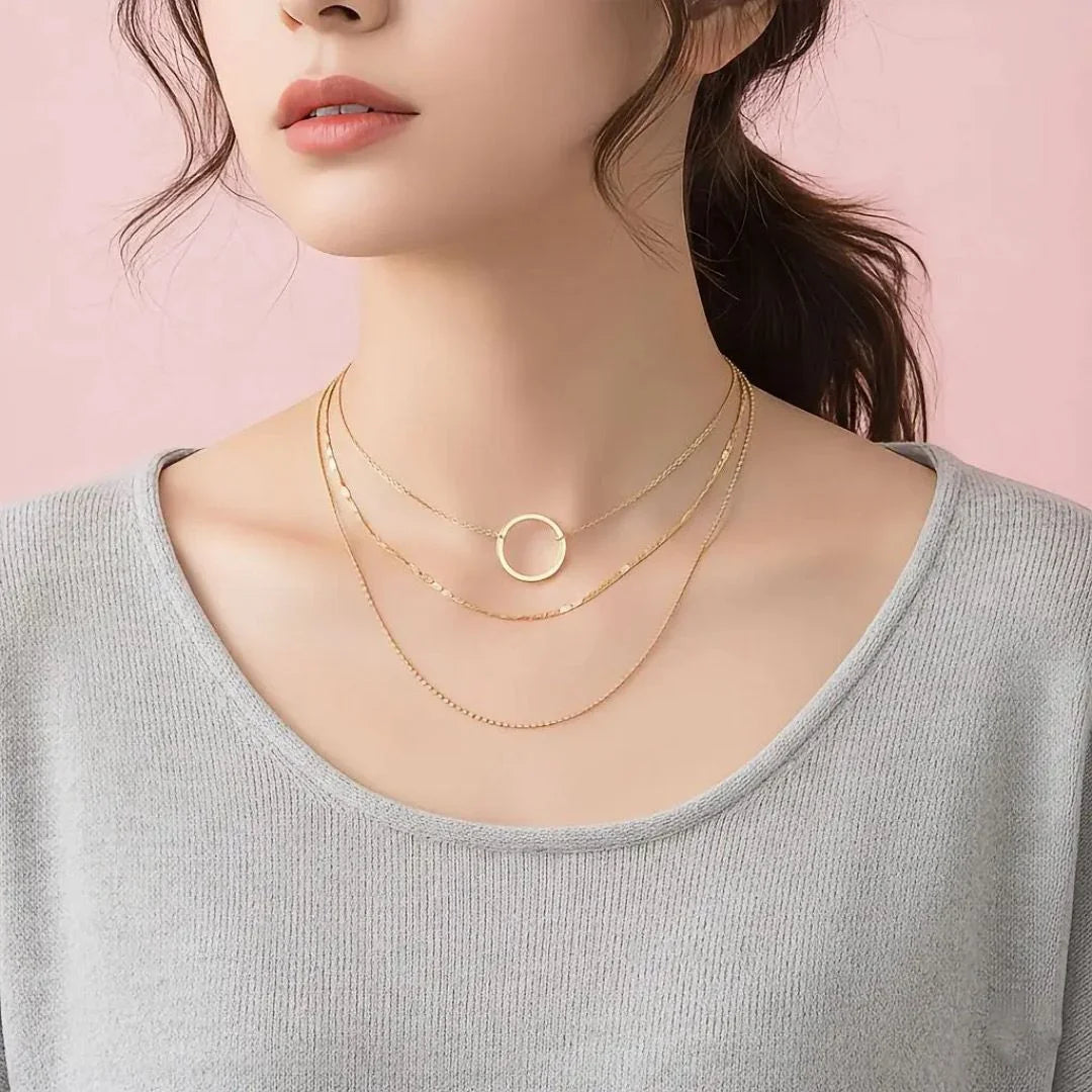 Woman wearing a gold necklace with a pink background