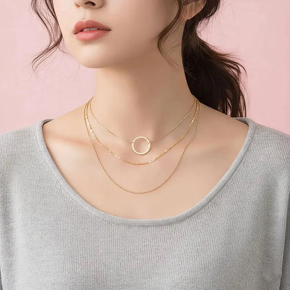 Woman wearing a gold necklace with a pink background