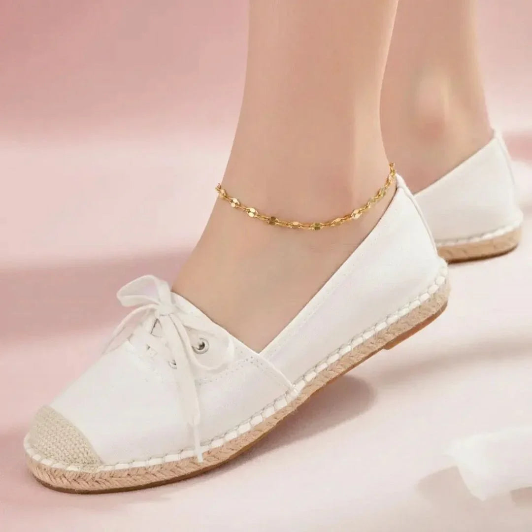 White sneakers with gold accents on a pink background