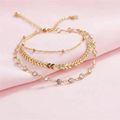 Gold bracelets with crystal accents on a pink fabric background