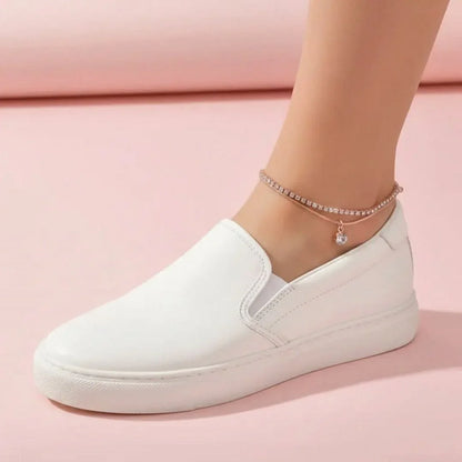 White slip-on shoe worn on a pink background