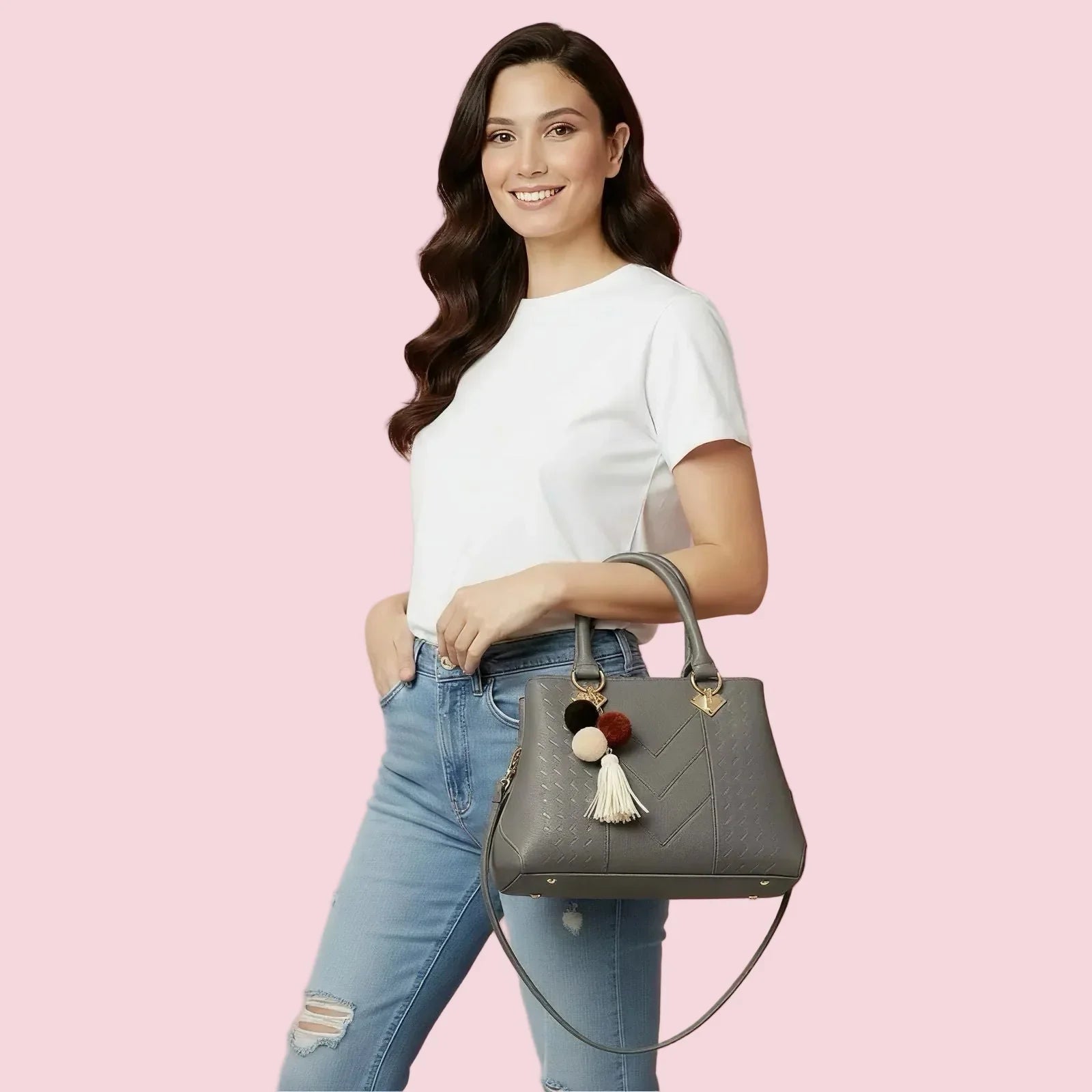 Woman holding a gray handbag with colorful tassels against a pink background