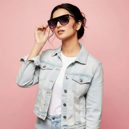 Woman wearing a light blue denim jacket and sunglasses on a pink background