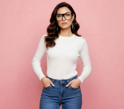 Woman wearing a white long-sleeve top and blue jeans against a pink background