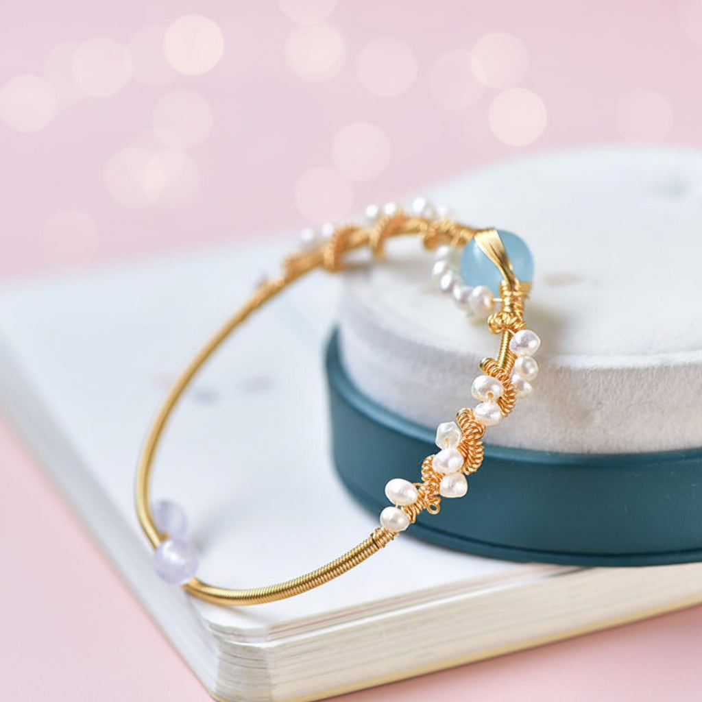 Gold bracelet with pearls on a white surface with a blurred background