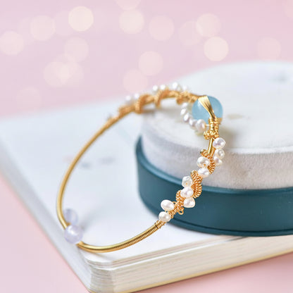 Gold bracelet with pearls on a white surface with a blurred background