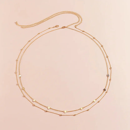 Gold necklace with small beads on a beige background